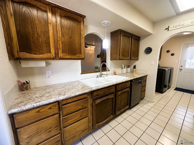 kitchen featuring black dishwasher, washer and dryer, backsplash, and a sink