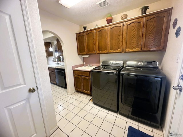 laundry area with arched walkways, washer and clothes dryer, visible vents, cabinet space, and a sink