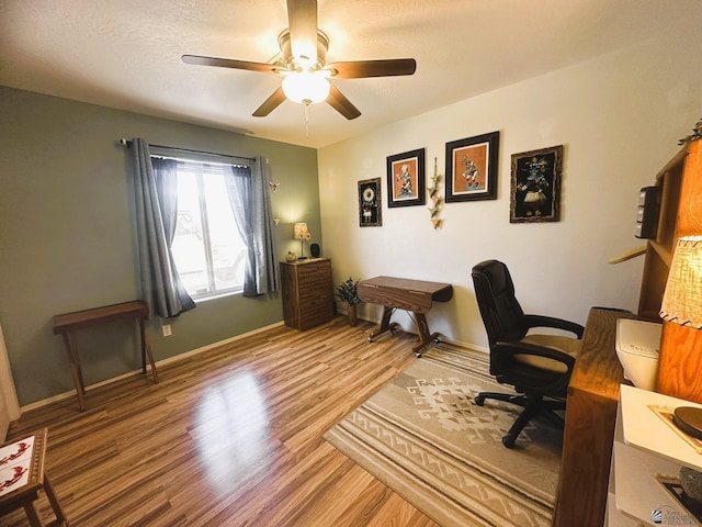 home office with a textured ceiling, wood finished floors, a ceiling fan, and baseboards