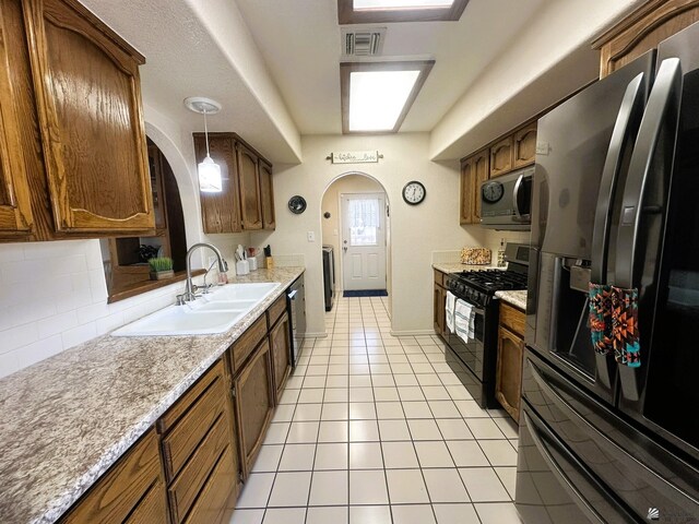 kitchen featuring arched walkways, visible vents, backsplash, appliances with stainless steel finishes, and a sink