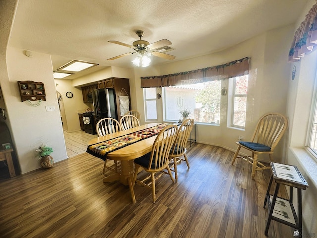 dining space with a ceiling fan, visible vents, a textured ceiling, and wood finished floors