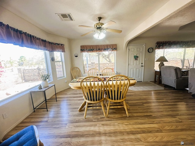 dining room featuring baseboards, ceiling fan, visible vents, and wood finished floors