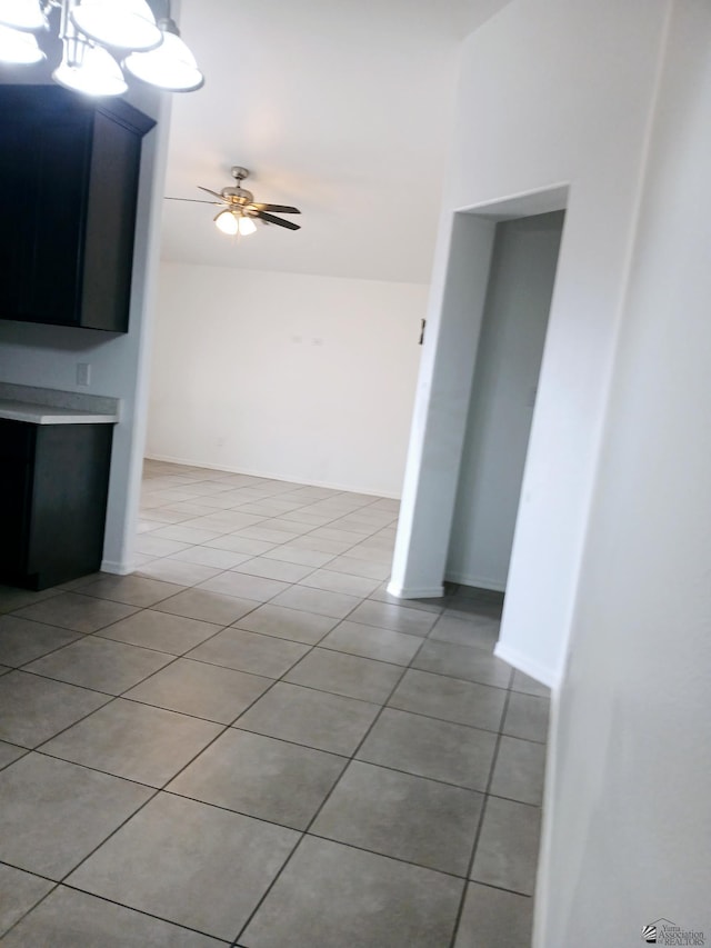 unfurnished living room featuring ceiling fan with notable chandelier and light tile patterned floors