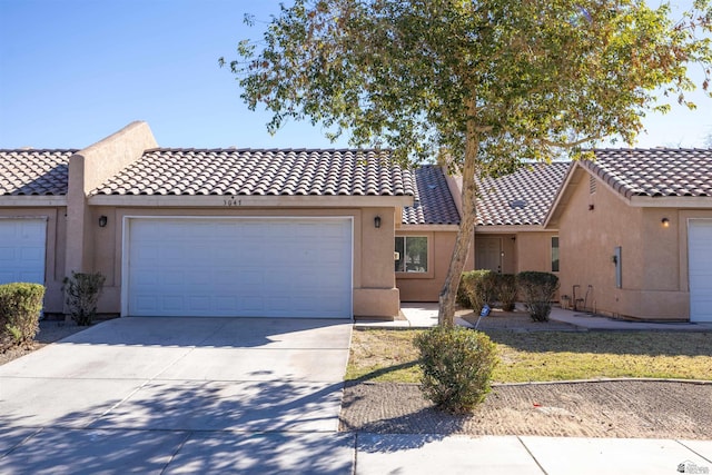 view of front of property with concrete driveway, an attached garage, a tile roof, and stucco siding