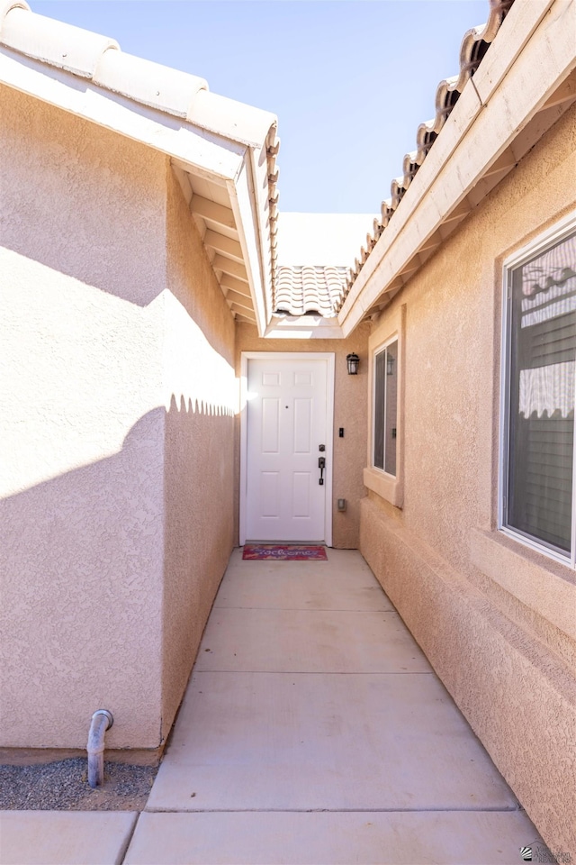 exterior space with a patio area, a tile roof, and stucco siding