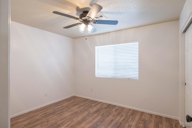 spare room with ceiling fan, a textured ceiling, baseboards, and wood finished floors