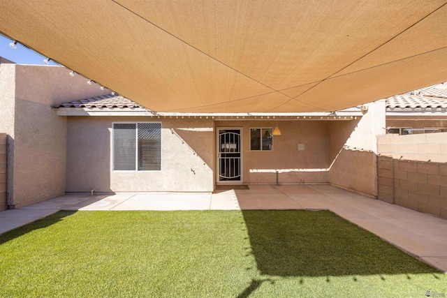 back of property featuring a patio, a tiled roof, fence, a yard, and stucco siding