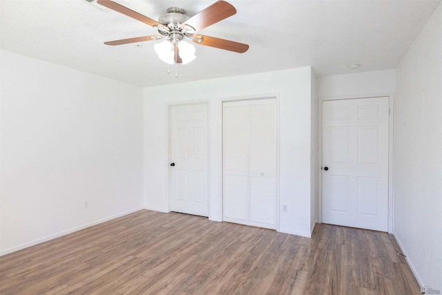 unfurnished bedroom with a ceiling fan, a closet, baseboards, and wood finished floors