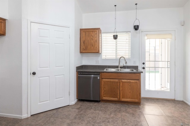 kitchen with pendant lighting, brown cabinets, dark countertops, a sink, and dishwasher