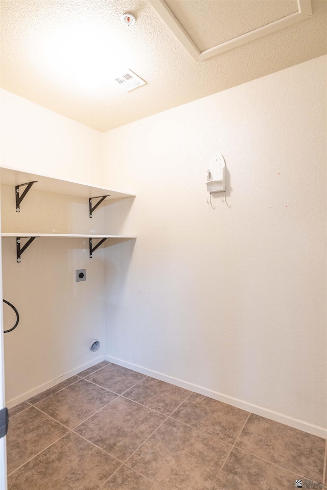 washroom featuring laundry area, baseboards, visible vents, dark tile patterned flooring, and electric dryer hookup