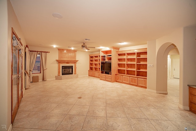 unfurnished living room with ceiling fan, a tiled fireplace, and light tile patterned floors