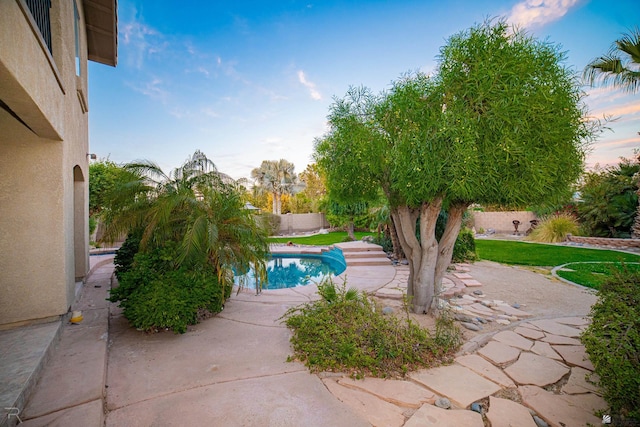 pool at dusk with a patio area