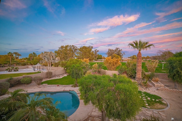 pool at dusk featuring a patio area