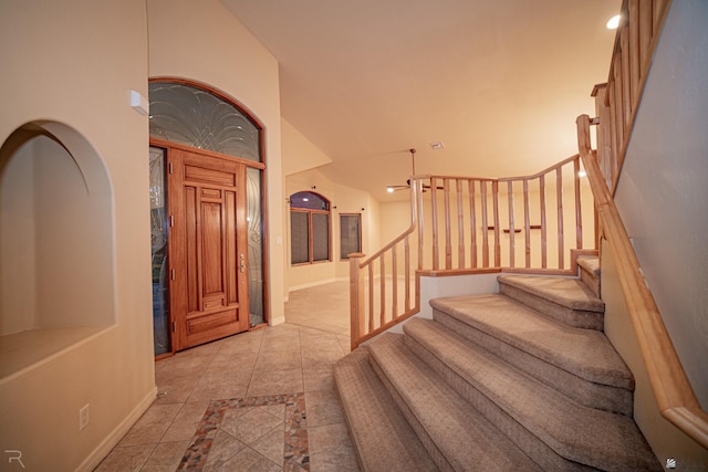 foyer entrance with vaulted ceiling and light tile patterned flooring