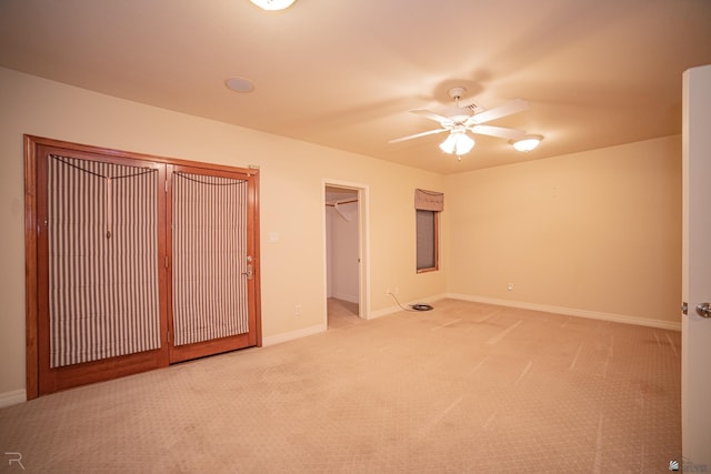 unfurnished bedroom featuring ceiling fan, light colored carpet, and a spacious closet