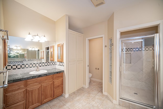 bathroom featuring a shower with shower door, tasteful backsplash, tile patterned flooring, vanity, and toilet