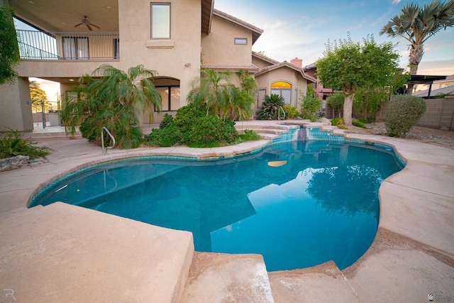 pool at dusk featuring ceiling fan