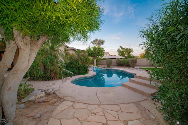 pool at dusk with a patio area