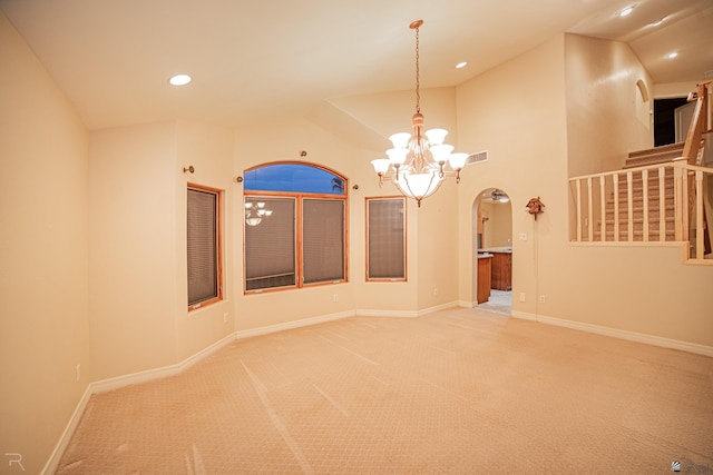 carpeted spare room with vaulted ceiling and a notable chandelier