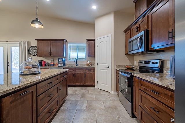 kitchen featuring sink, hanging light fixtures, dark brown cabinets, stainless steel appliances, and light stone countertops