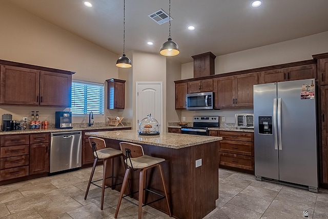 kitchen with dark brown cabinetry, stainless steel appliances, a center island, and hanging light fixtures