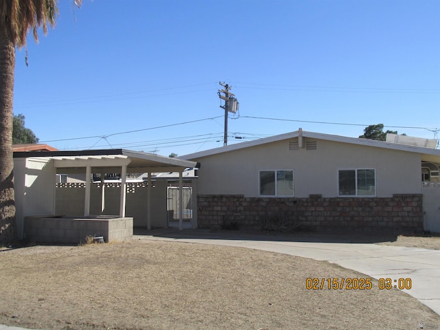 view of front of home featuring driveway, fence, a carport, and stucco siding