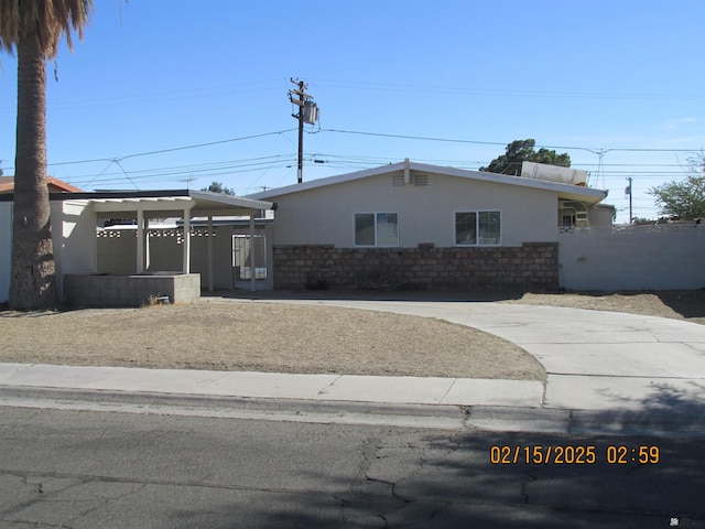 view of front facade featuring a carport, fence, and stucco siding