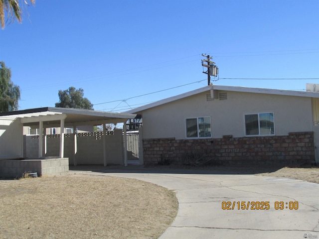 view of home's exterior with concrete driveway, stone siding, a gate, and stucco siding