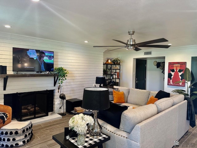 living room featuring a fireplace, ceiling fan, and crown molding