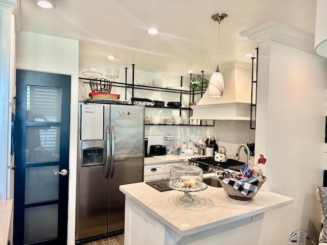 kitchen featuring white cabinets, stainless steel fridge, light stone countertops, decorative light fixtures, and custom range hood