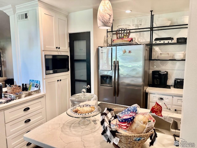 kitchen with stainless steel fridge with ice dispenser, light stone countertops, built in microwave, tasteful backsplash, and white cabinetry