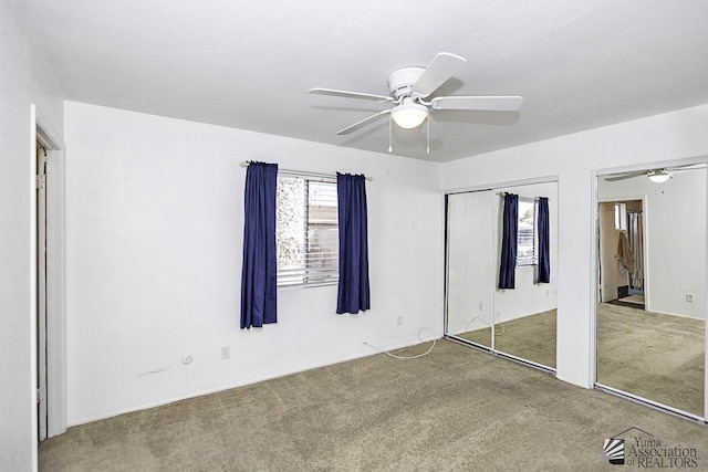 unfurnished bedroom with multiple closets, ceiling fan, and carpet floors