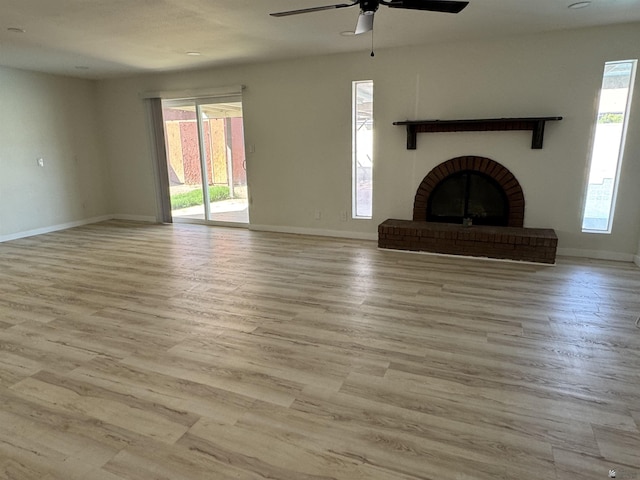 unfurnished living room featuring a fireplace, a ceiling fan, baseboards, and wood finished floors