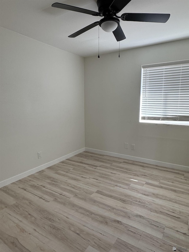 empty room with baseboards, wood finished floors, and a ceiling fan