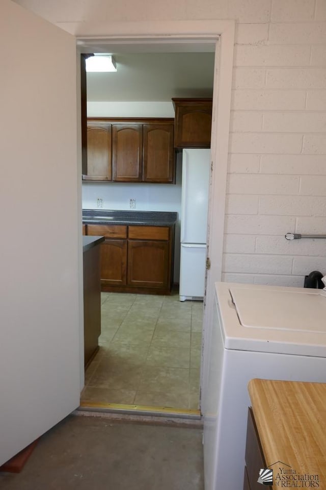 kitchen featuring washer / clothes dryer, concrete floors, and freestanding refrigerator