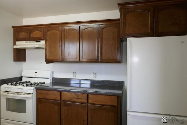 kitchen featuring under cabinet range hood, white appliances, and dark stone countertops