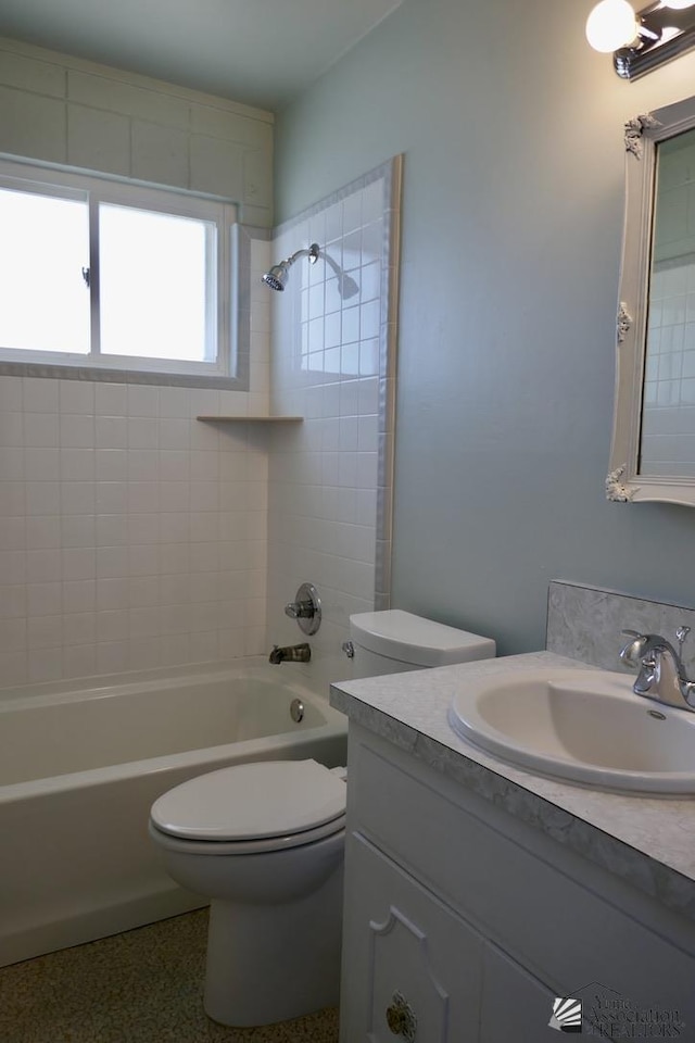 bathroom with speckled floor, toilet, shower / washtub combination, and vanity