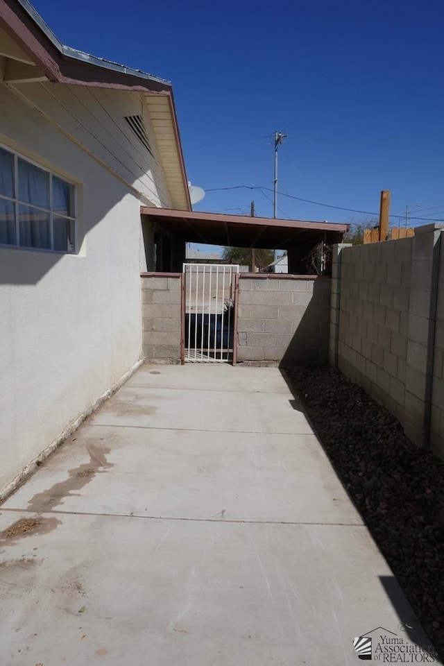 view of patio featuring an attached carport, a gate, and fence