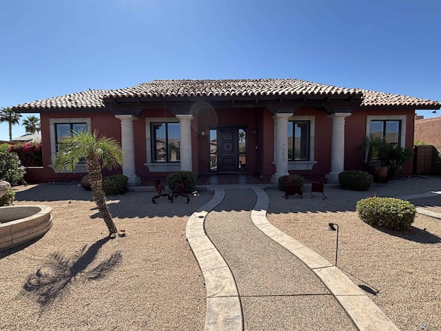 rear view of house featuring stucco siding, a tile roof, and covered porch