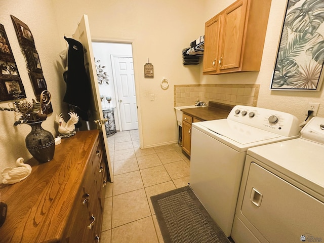 washroom with cabinet space, washing machine and dryer, baseboards, and light tile patterned floors