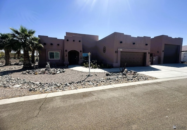 adobe home featuring concrete driveway, a garage, and stucco siding