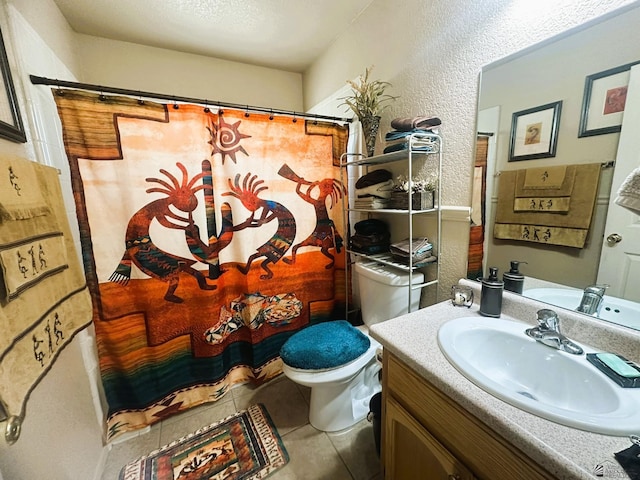 full bath with tile patterned floors, vanity, a textured wall, and toilet