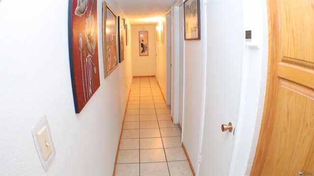 corridor with a textured ceiling and light tile patterned flooring