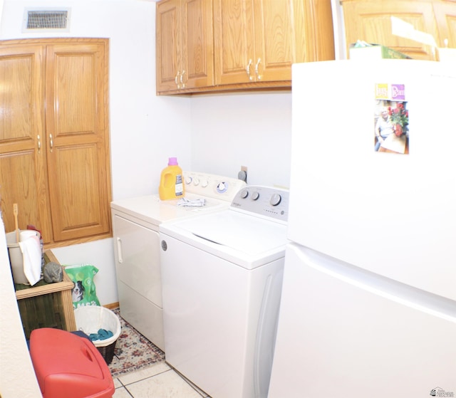 laundry room featuring washer and dryer, light tile patterned floors, and cabinets