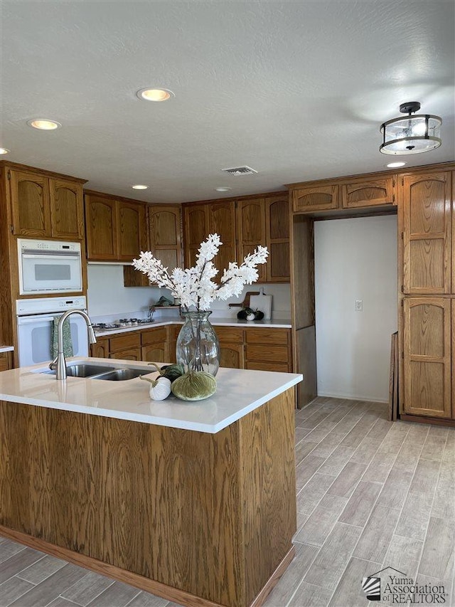 kitchen with white oven, kitchen peninsula, sink, and gas cooktop