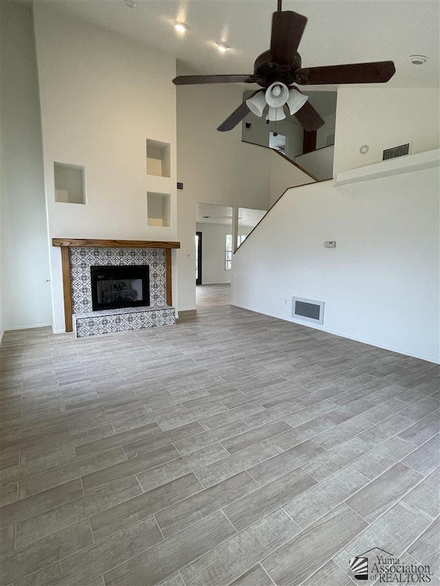 unfurnished living room featuring ceiling fan, a fireplace, and high vaulted ceiling