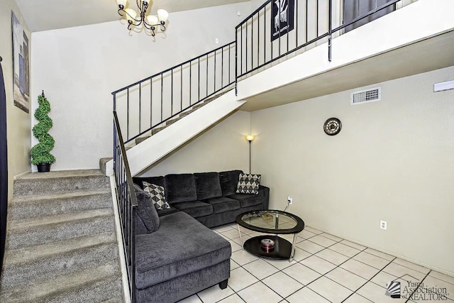 living area with light tile patterned flooring, a high ceiling, visible vents, stairway, and an inviting chandelier