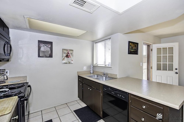 kitchen featuring dark brown cabinetry, a sink, visible vents, light countertops, and black appliances