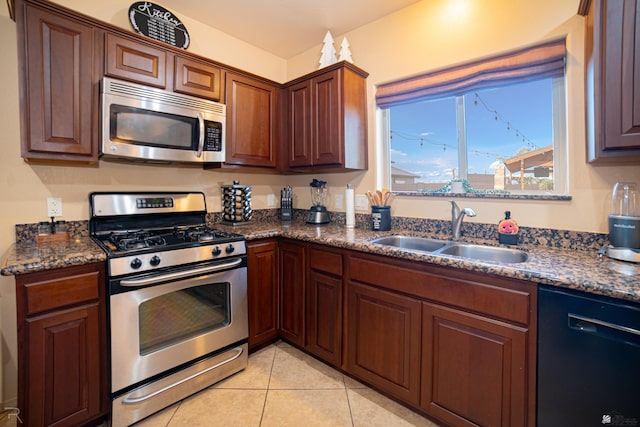 kitchen with dark stone countertops, sink, stainless steel appliances, and light tile patterned flooring