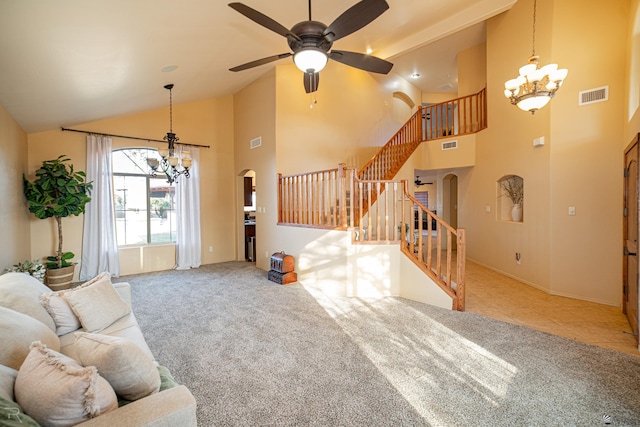 carpeted living room with ceiling fan with notable chandelier and high vaulted ceiling